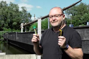 Uwe Kühn mit Geocache und GPS-Gerät vor einem Ruhrkohleschiff (© Foto: Marek Firlej)